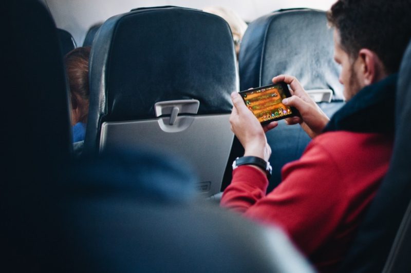 Fluggast mit Smartphone an Bord eines Flugzeugs (Foto: Reshot / Lelia Milaya).